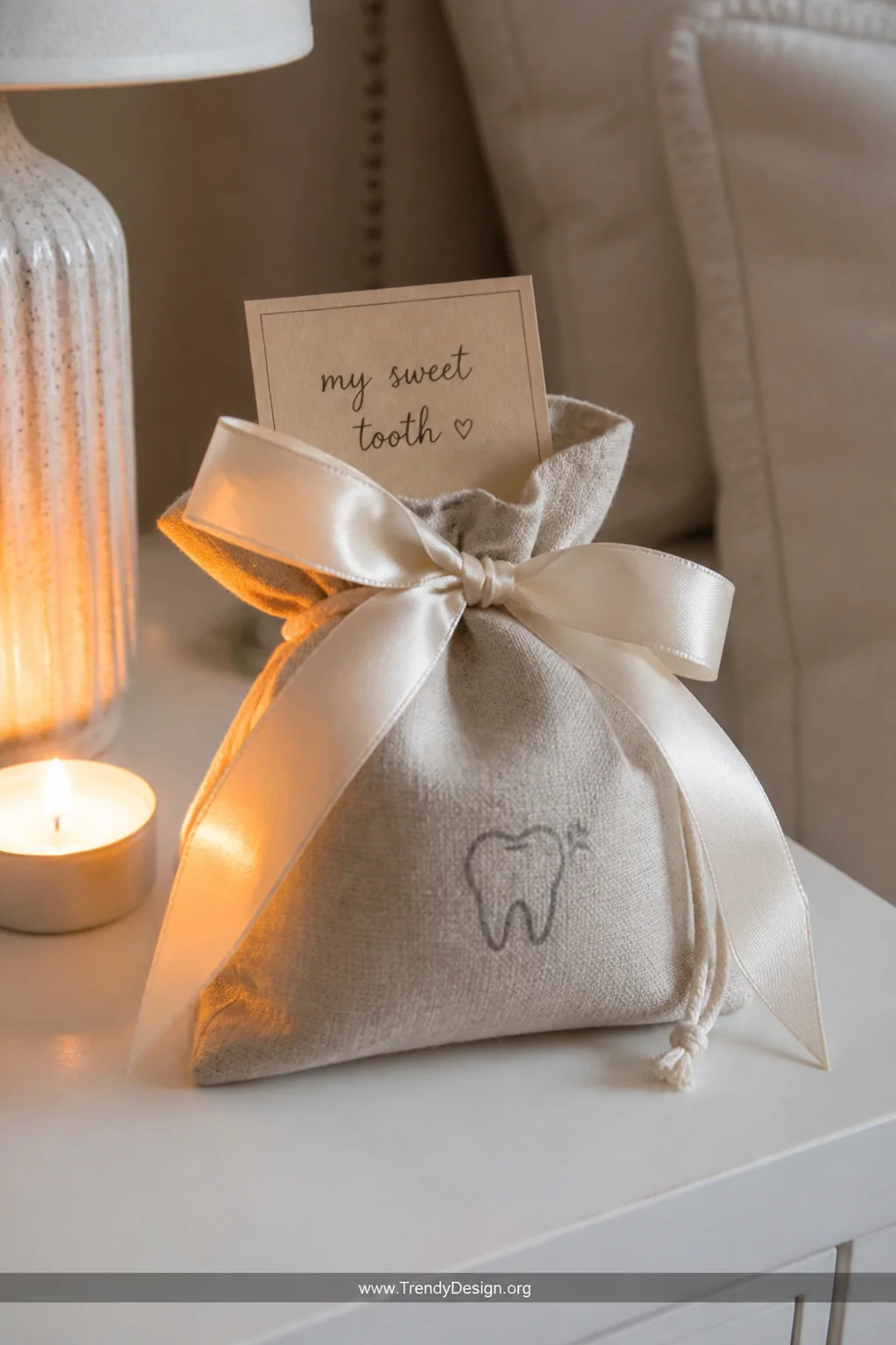 Close-up detail shot of a small natural linen drawstring bag tied with a wide ivory satin ribbon bow on a white bedside table
