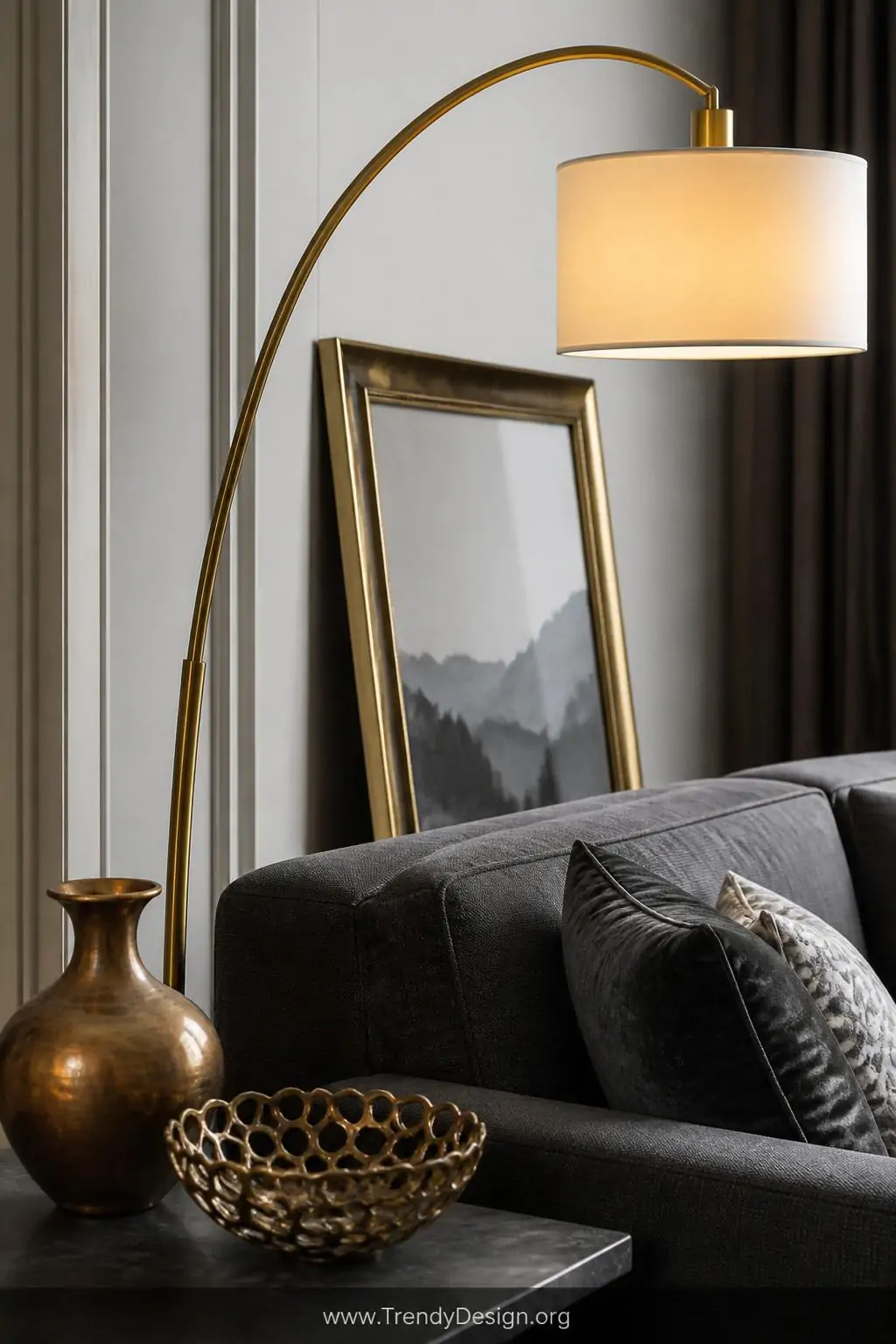 Close-up photorealistic interior vignette of a dark grey sofa's side table area featuring an arched brass floor lamp with a w