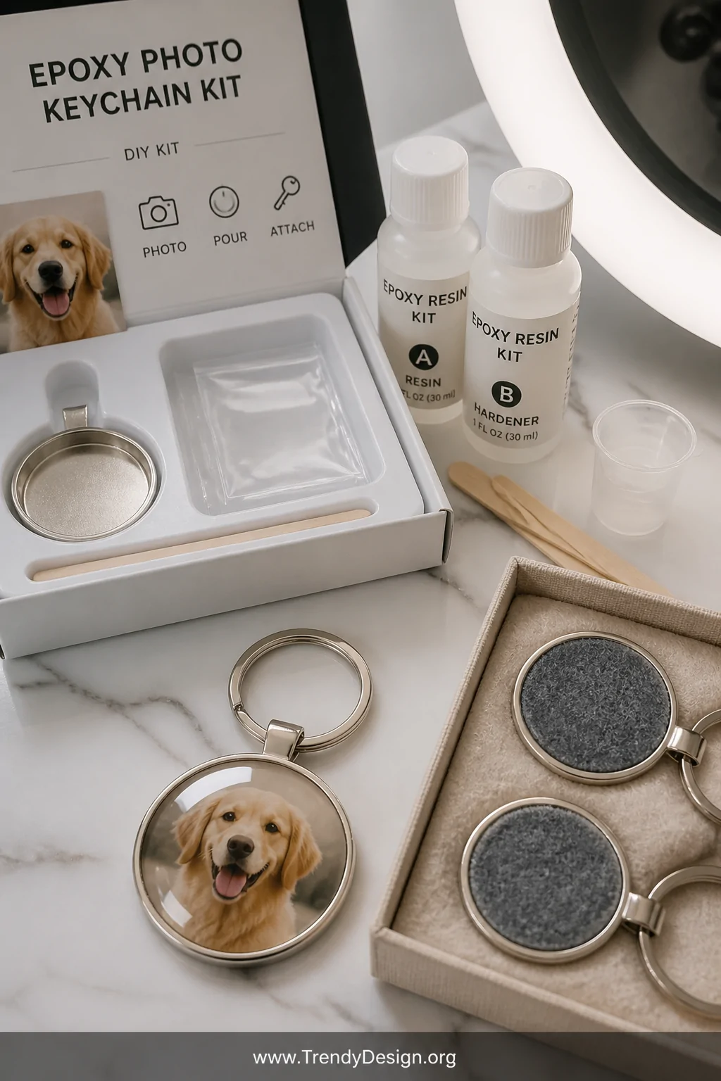 A clean white resin studio desktop with an epoxy photo keychain kit opened to reveal two-part resin bottles, a precision-trim
