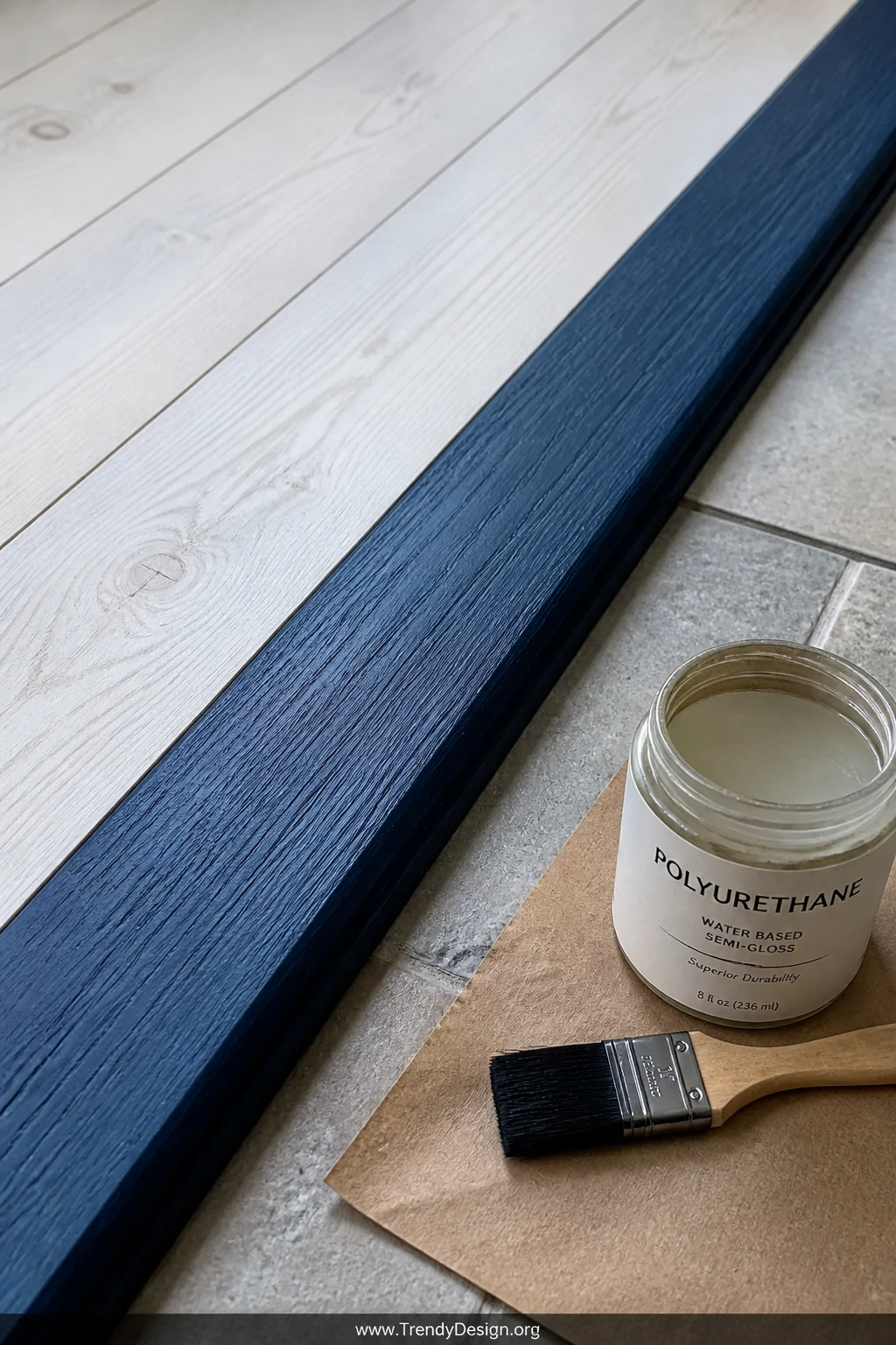 Detail closeup of a raw wood transition strip freshly hand-stained in deep navy blue paint, installed between light whitewash