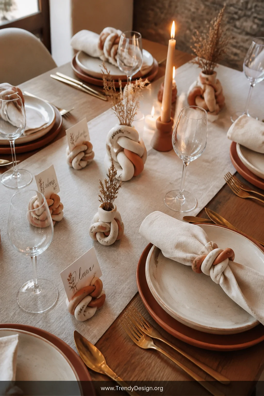 Medium overhead shot of an elegantly set dining table featuring handmade polymer clay napkin rings twisted from cream and ter