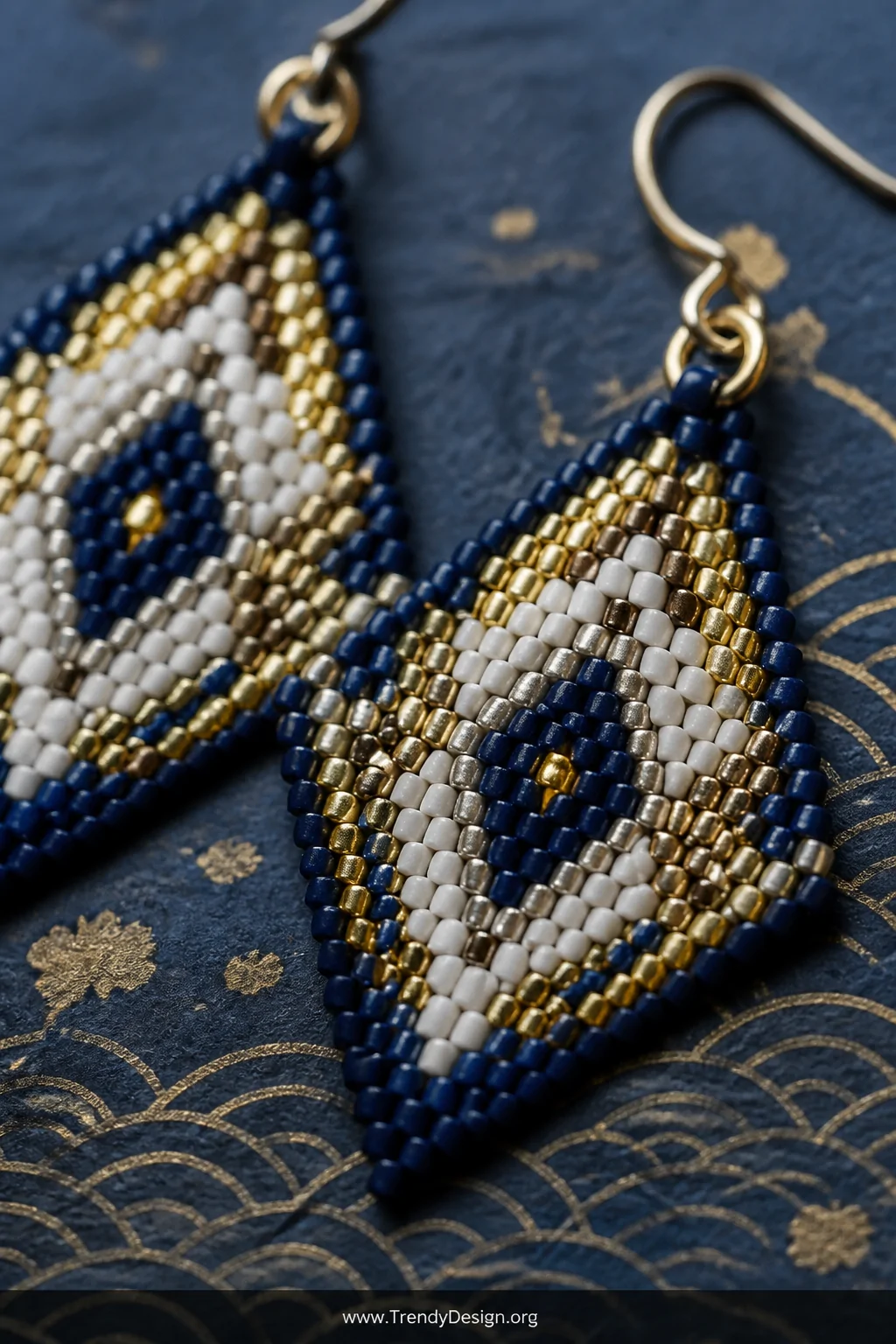 An extreme macro closeup shot of a pair of Miyuki glass bead earrings resting on a sheet of deep navy Japanese washi paper, t