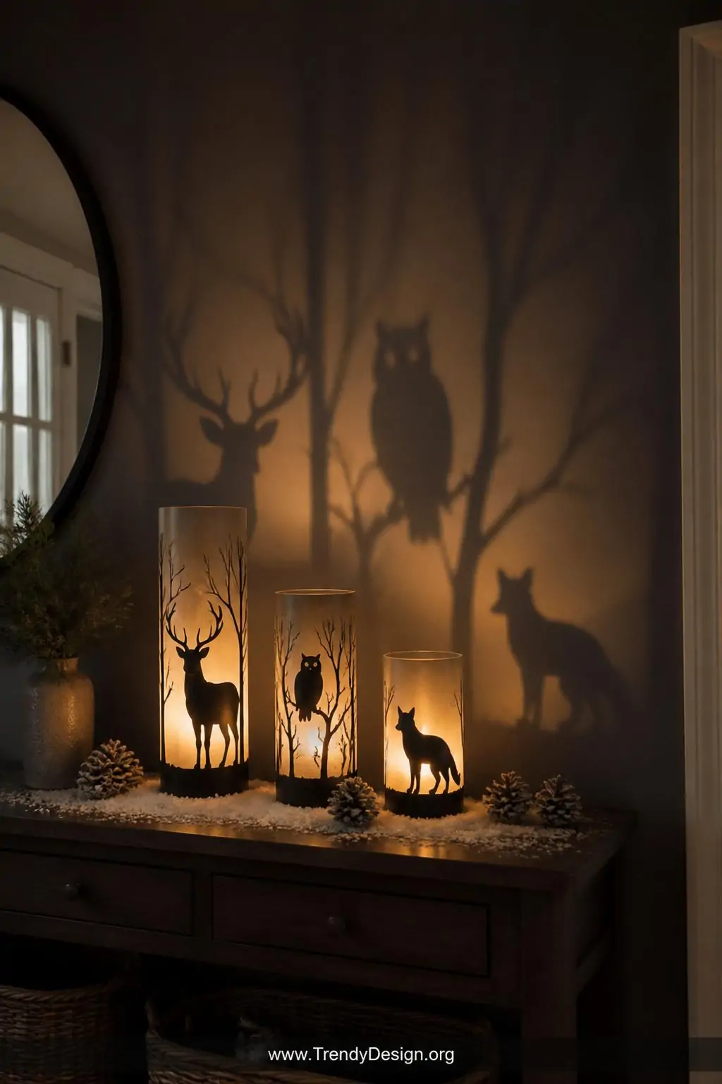 A moody atmospheric wide shot of an entryway console table featuring three glass cylinder lanterns of graduated heights each 