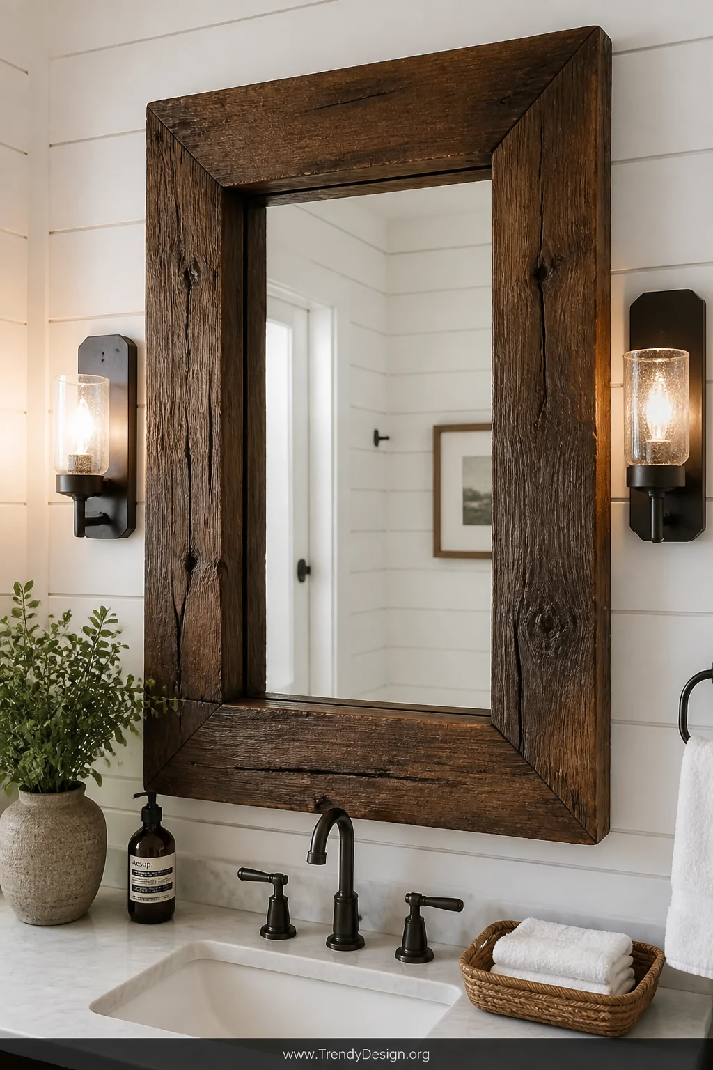 Medium shot focused on a chunky rough-cut lumber mirror frame stained in rich dark walnut mounted above a bathroom vanity, th