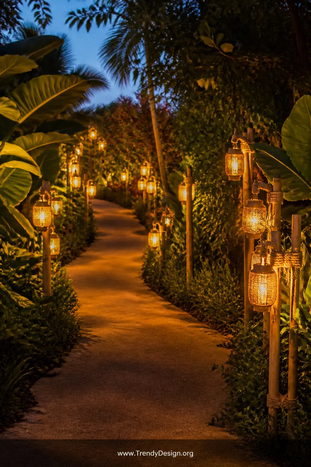 A wide shot of a winding garden path lined with bamboo stake lanterns at varying heights, small glass jars wired to the bambo