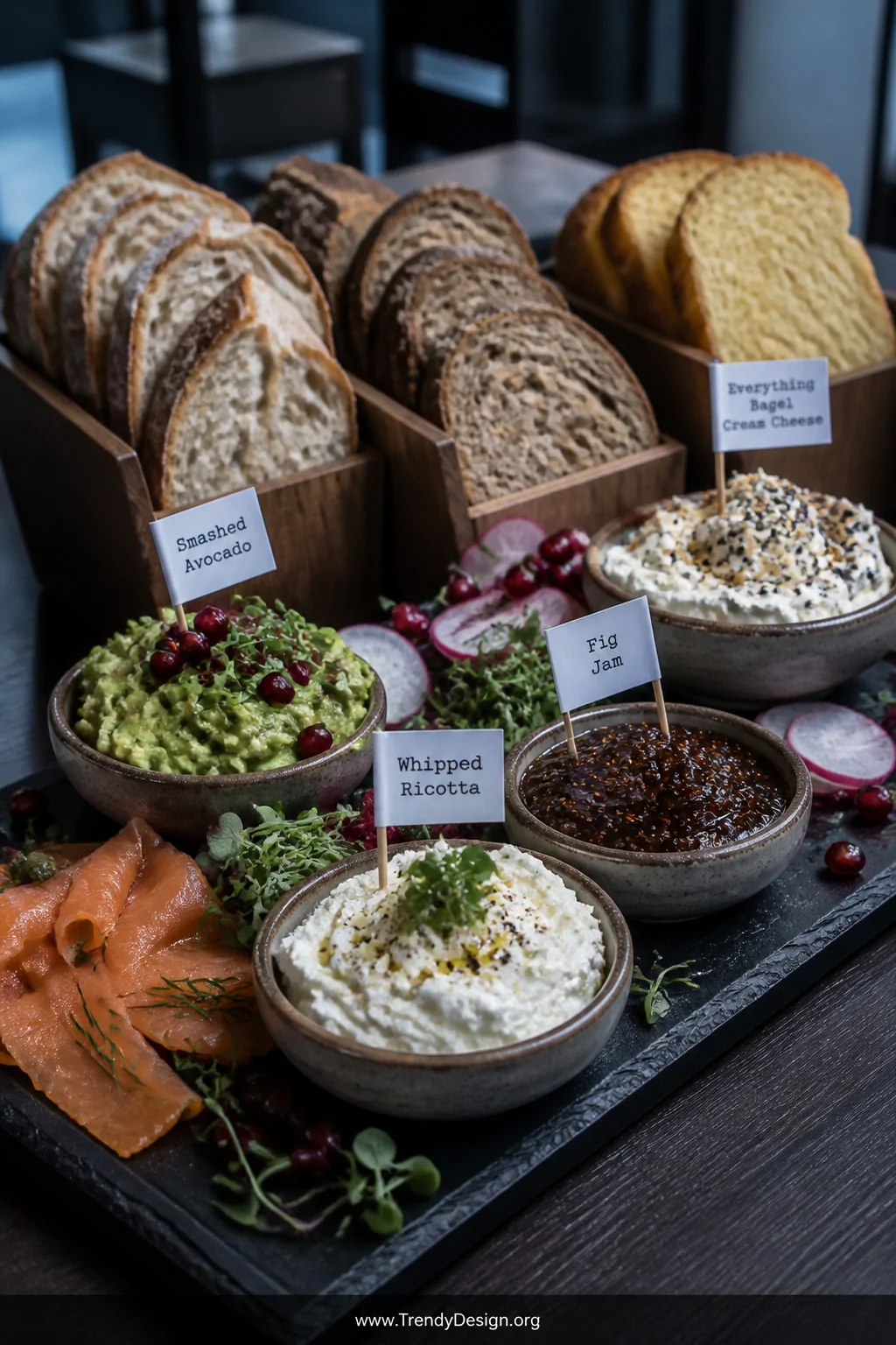 Close-up detail shot of slate boards arranged on a dark wood surface holding small ceramic bowls of whipped ricotta, smashed 