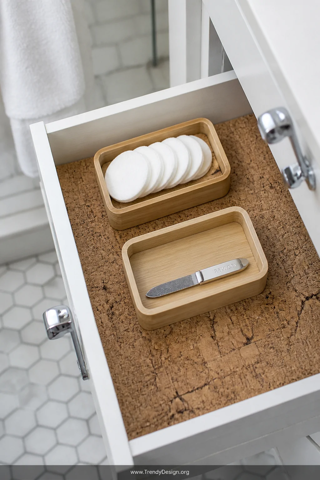 A close-up detail shot of a bathroom drawer interior lined with textured natural cork, topped with small bamboo organizers ho