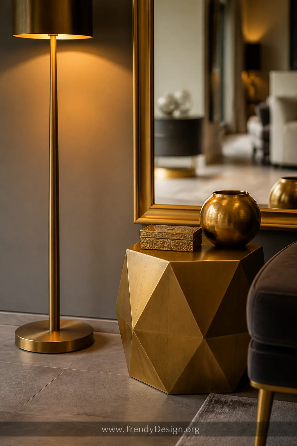 A closeup detail shot of layered warm brass and gold metal accents in a grey-floored living room, featuring a tall brushed br