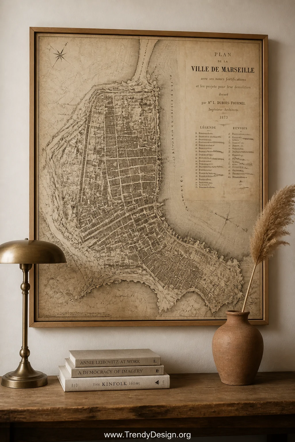 Medium shot of an oversized vintage sepia-toned antique city map print framed in simple raw wood, hung prominently on a warm 