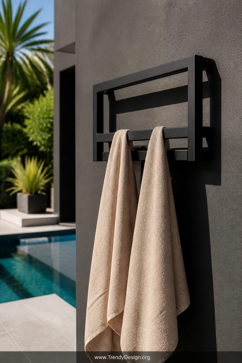 A medium shot of a powder-coated matte black wall-mounted metal towel rack installed on a charcoal exterior wall beside a poo