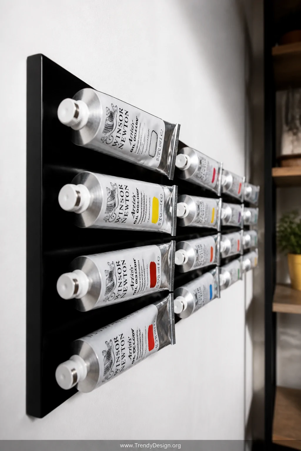 Close-up detail shot of a sleek black magnetic knife strip mounted at eye level on a white plaster wall, rows of metal paint 