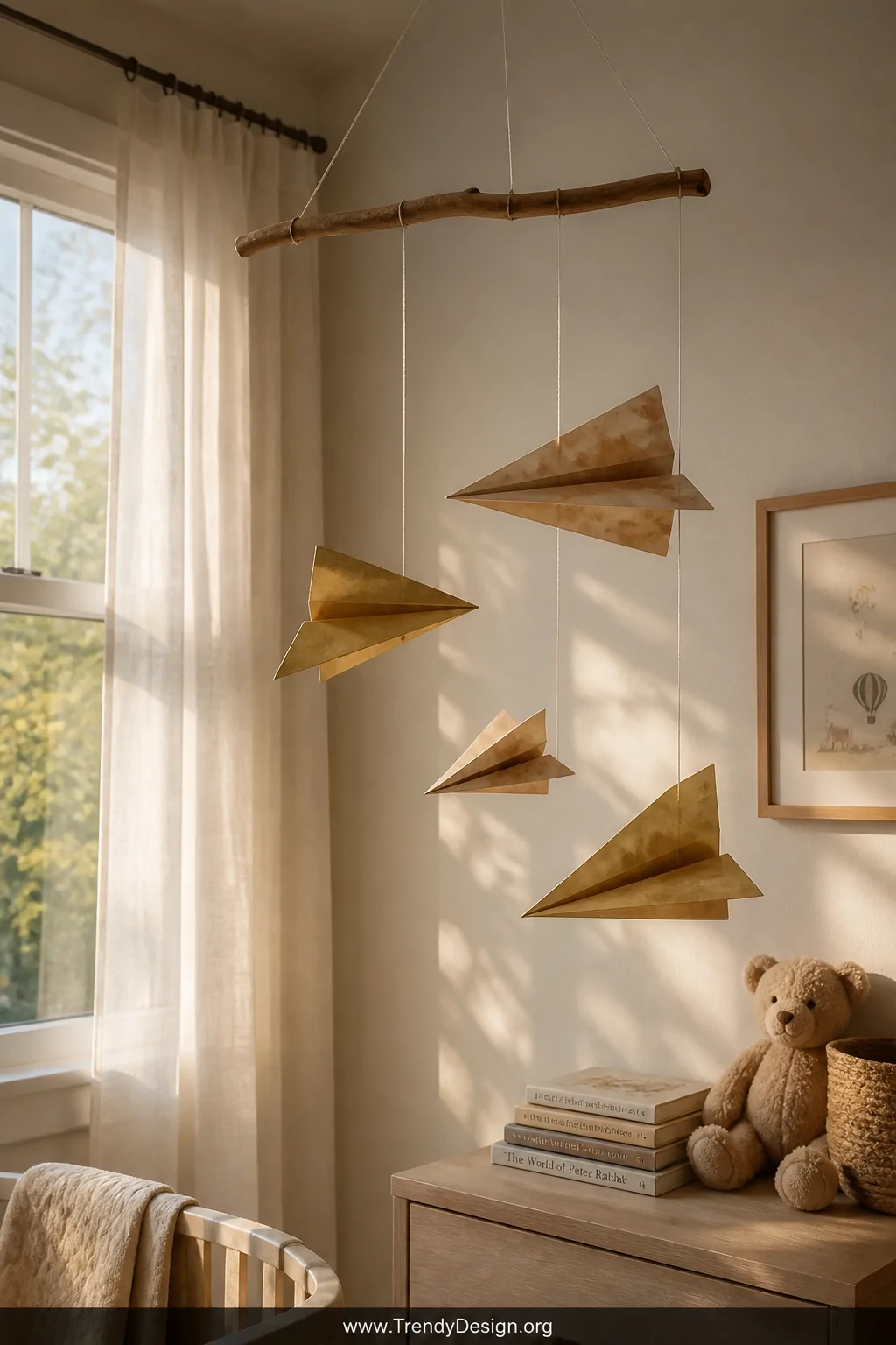 Wide shot of a softly lit nursery corner near a large window with sheer white curtains, featuring a handmade mobile hanging f