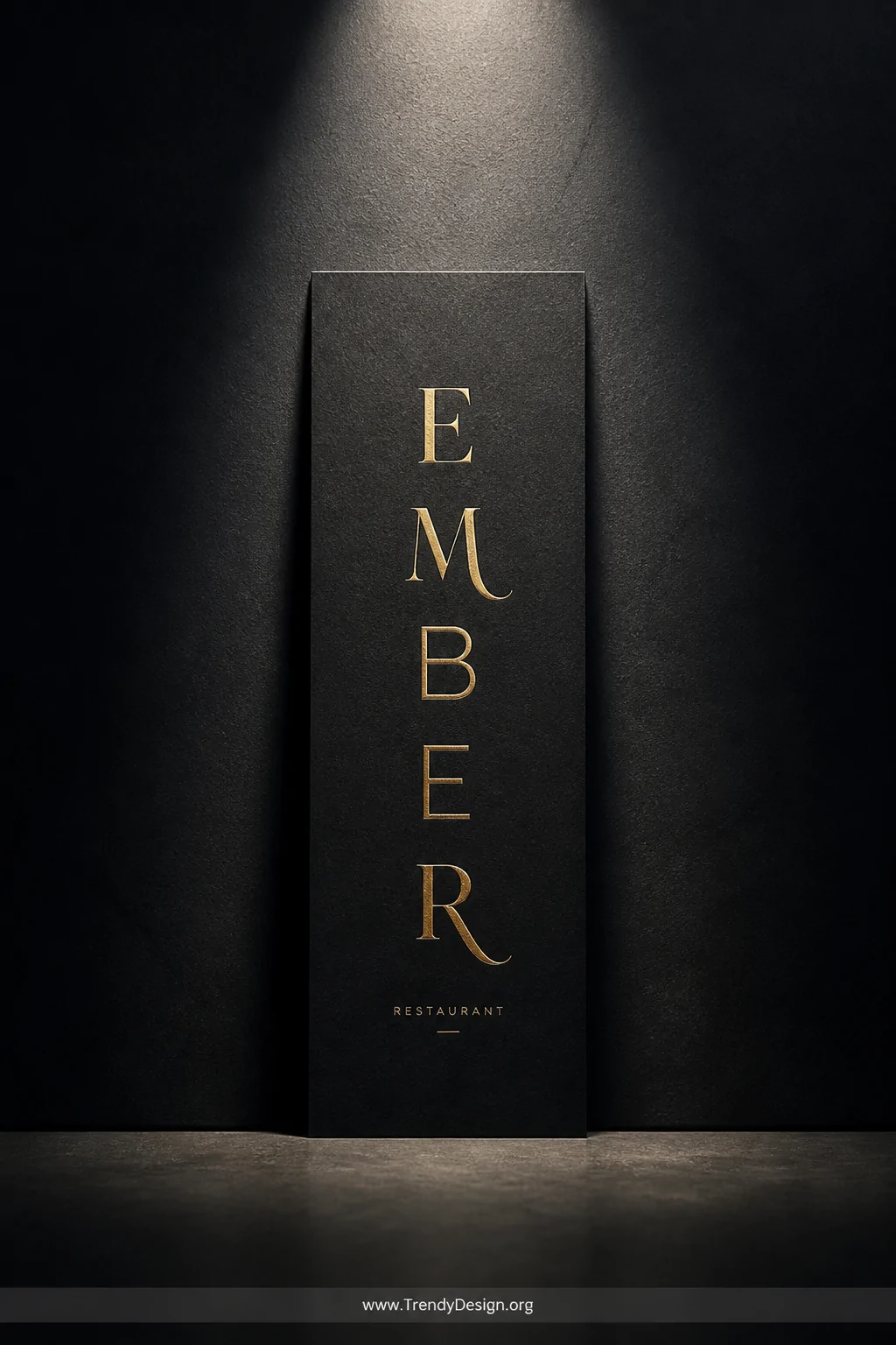 A medium shot of a single slimline card standing against a deep charcoal matte wall, featuring bold gold heat-embossed typogr