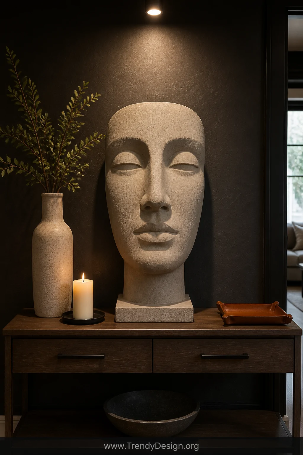 A medium shot of a entryway console table styled with an oversized monochromatic pale stone-toned clay head sculpture as the 