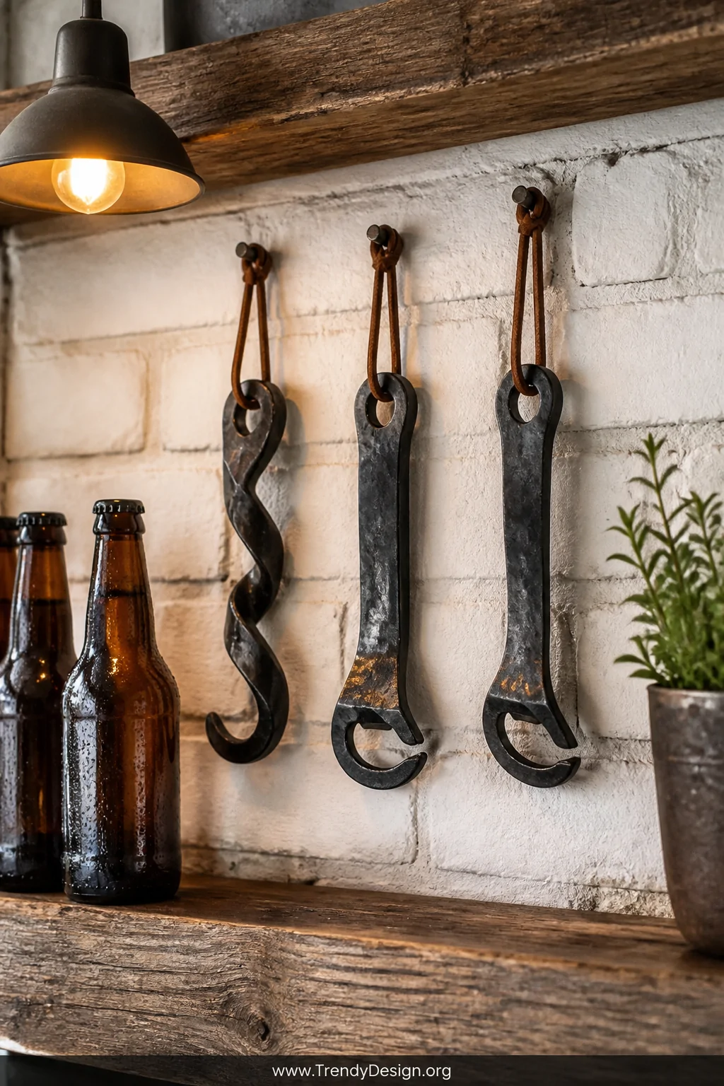 Medium shot of a reclaimed wood kitchen shelf displaying three hand-forged railroad spike bottle openers hanging from leather