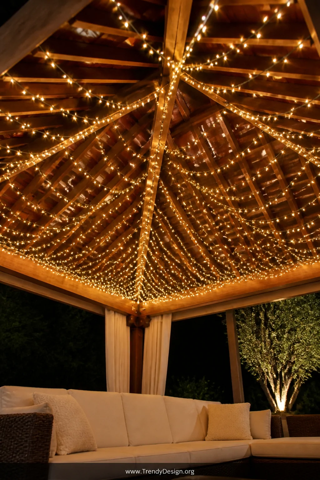 A wide upward-angle shot looking up at a gazebo ceiling covered in a dense zigzag weave of warm fairy lights strung back and 