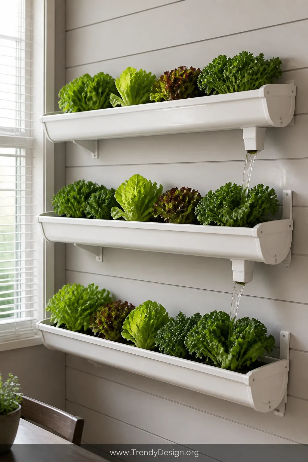 A styled interior wall displaying three stacked white-painted aluminum rain gutter sections mounted at slight cascading angle