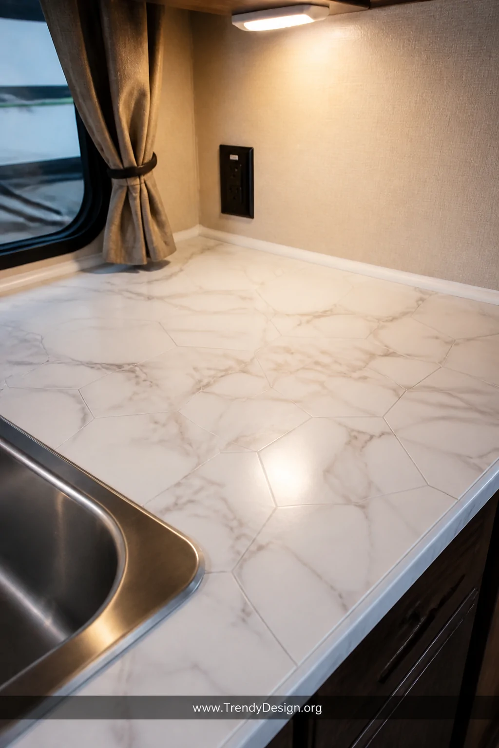 A close-up detail shot of a freshly installed peel-and-stick vinyl countertop inside a compact pop-up camper kitchen, featuri