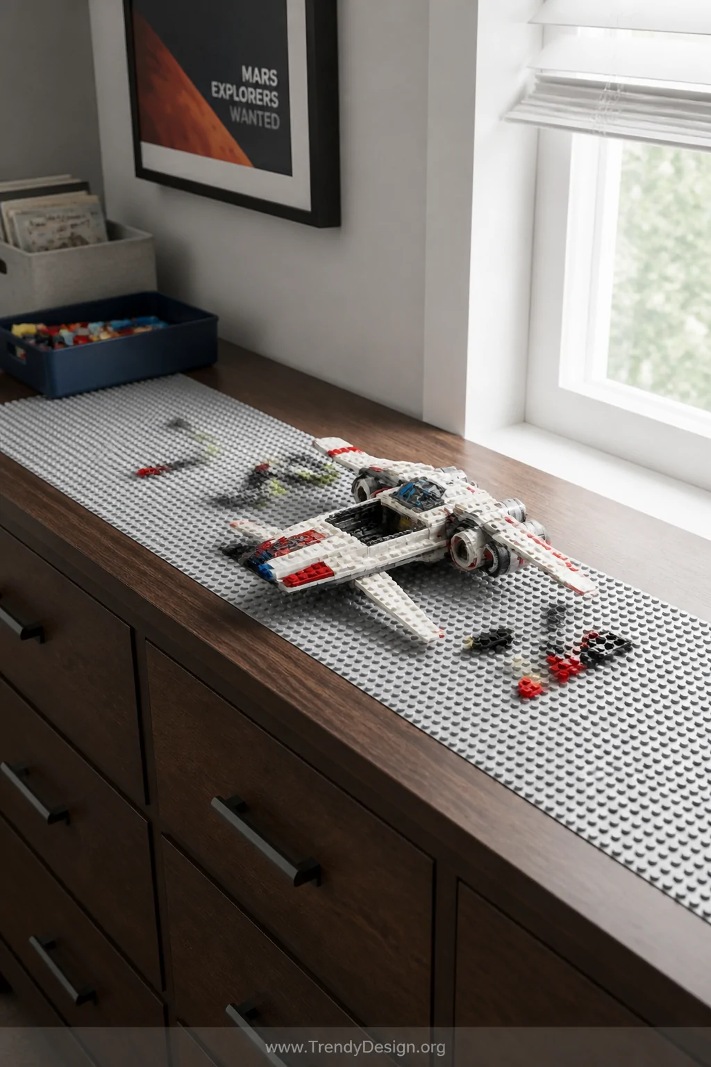 A medium shot of the top surface of a boy's dresser fitted with a neat strip of gray LEGO-compatible baseplates running its f