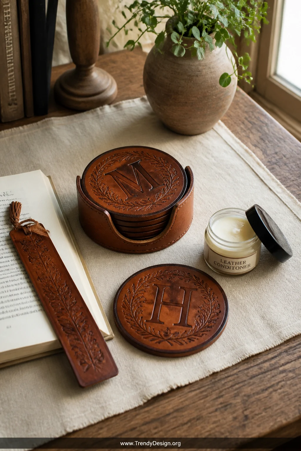 A medium shot of a rustic wooden desk surface styled with an artisanal vegetable-tanned leather coaster set featuring deeply 