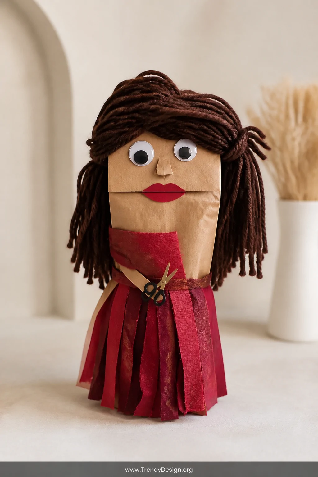 A medium shot of a brown paper bag hand puppet displayed upright against a soft neutral background, featuring dark dramatic y