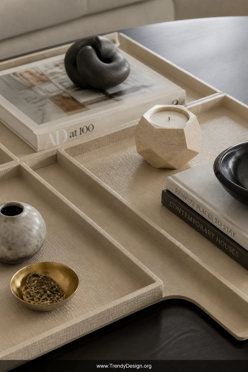 Close-up detail shot of a styled coffee table featuring a set of custom vacuum-formed shallow decorative trays in warm cream 