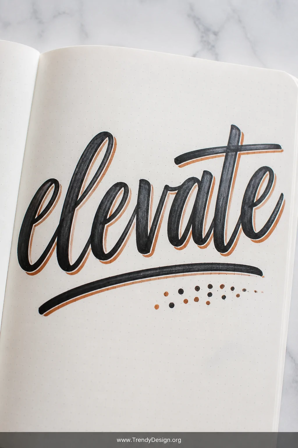 A closeup shot of a single journal page resting on a smooth white marble surface, showing wide brush-lettered typography stre