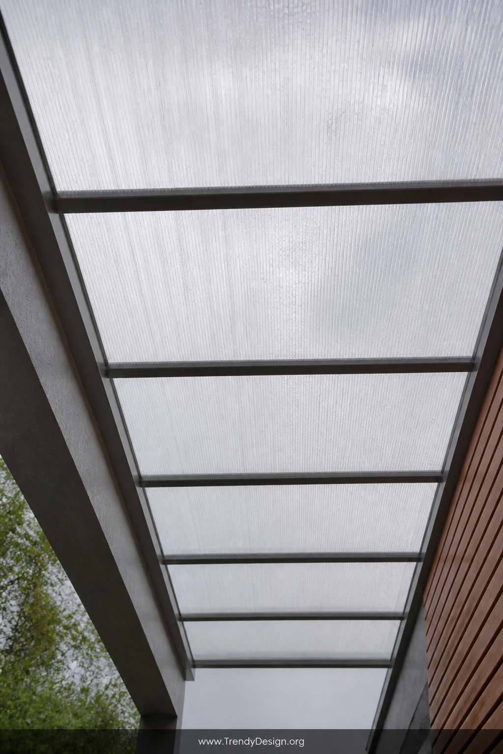 A detail shot looking upward through a polycarbonate roof walkway canopy, showcasing opal-tinted twin-wall translucent panels