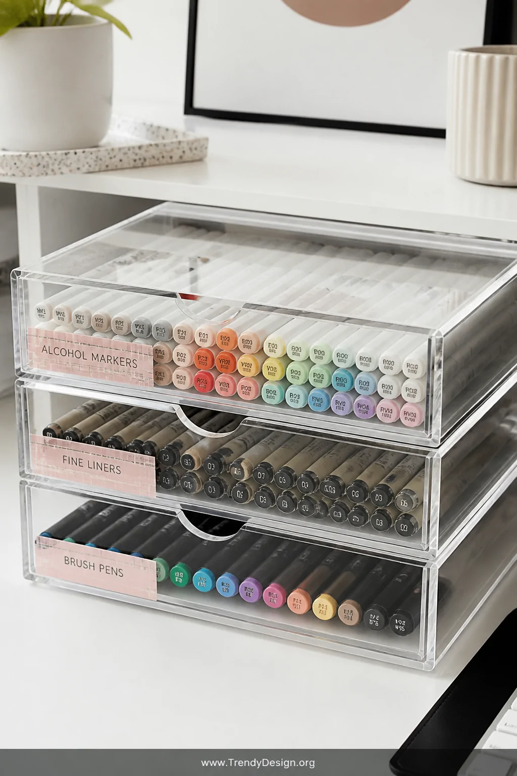 A closeup detail shot of a modern desk surface with three stacked clear acrylic drawers, each drawer visible and filled with 