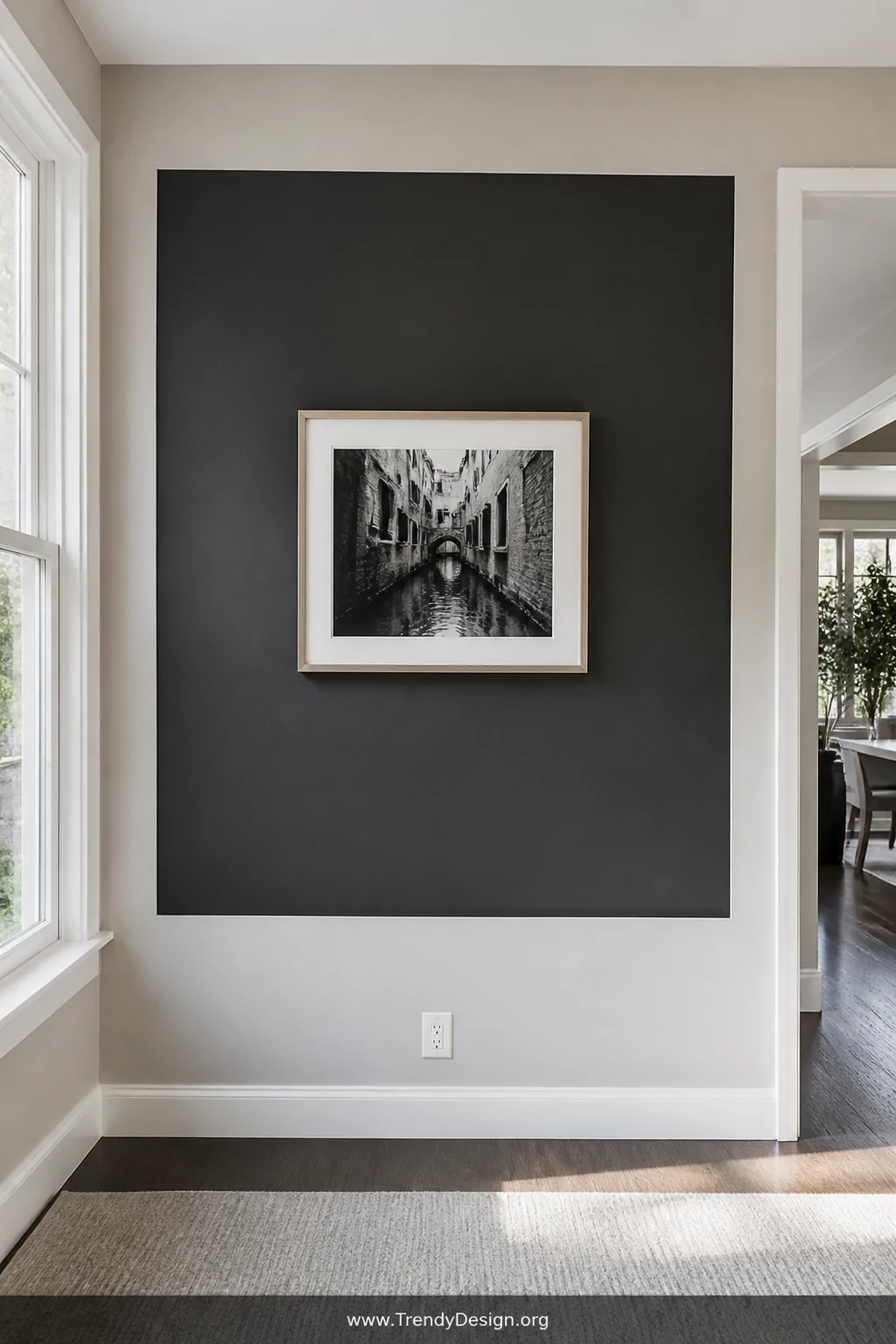 Wide shot of a bright interior wall where a bold dark painted rectangle acts as a faux frame, a light-colored physical frame 