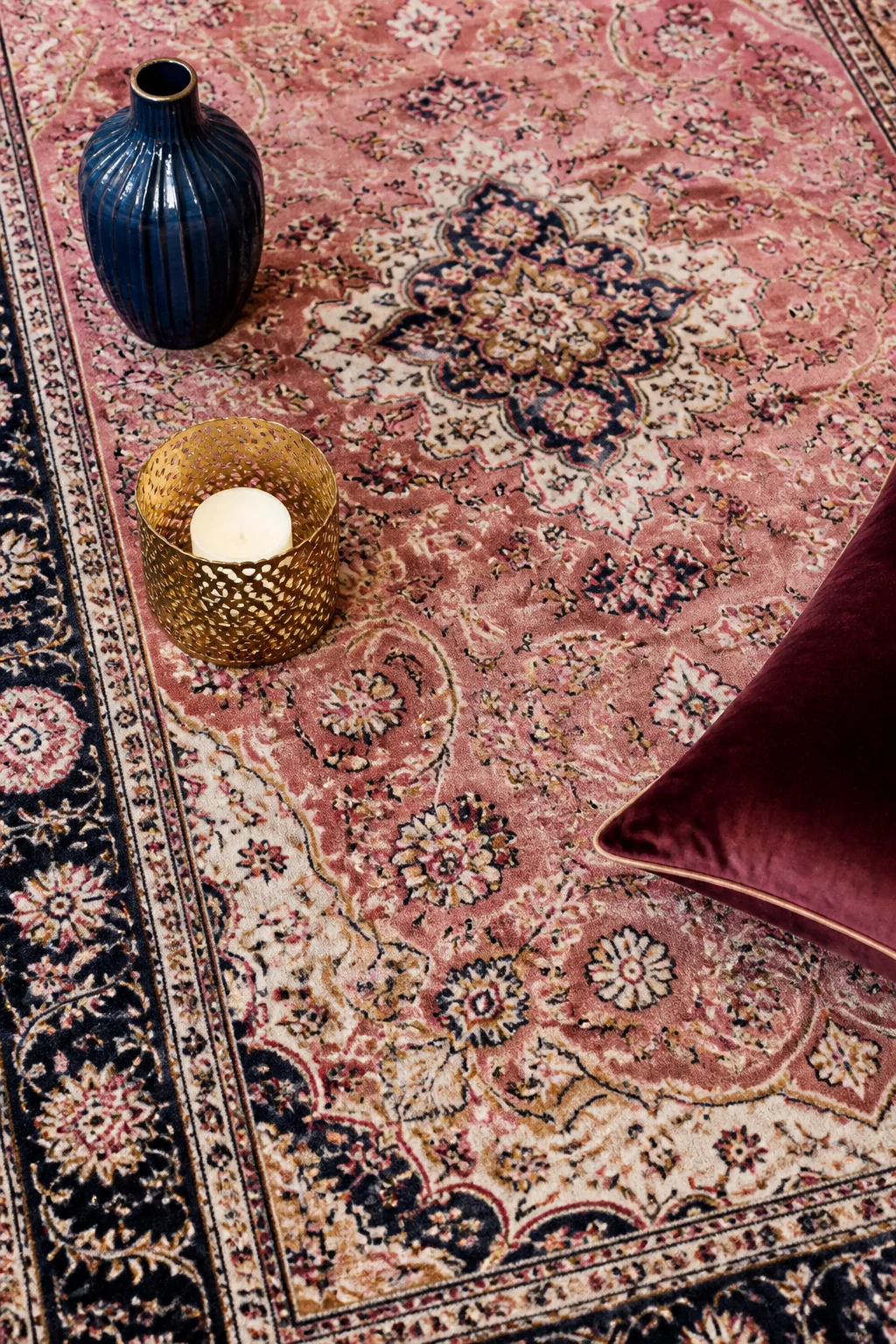 Closeup photorealistic styled detail shot of a pink Persian rug's medallion and border design with rose, ivory, navy, and gol