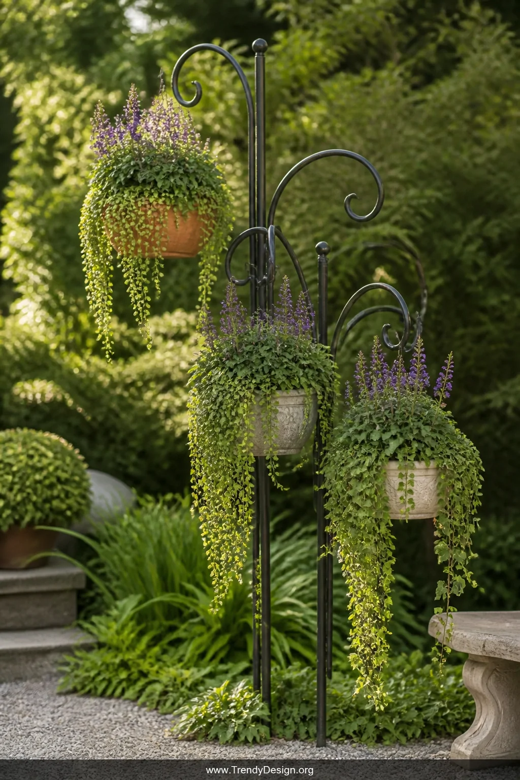 A wide outdoor garden shot of a tall black wrought-iron shepherds hook clustered with two others at varying heights, each arm