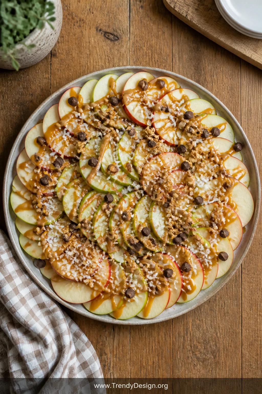 A wide overhead flat-lay shot of a large round ceramic serving platter covered in overlapping thinly sliced red and green app