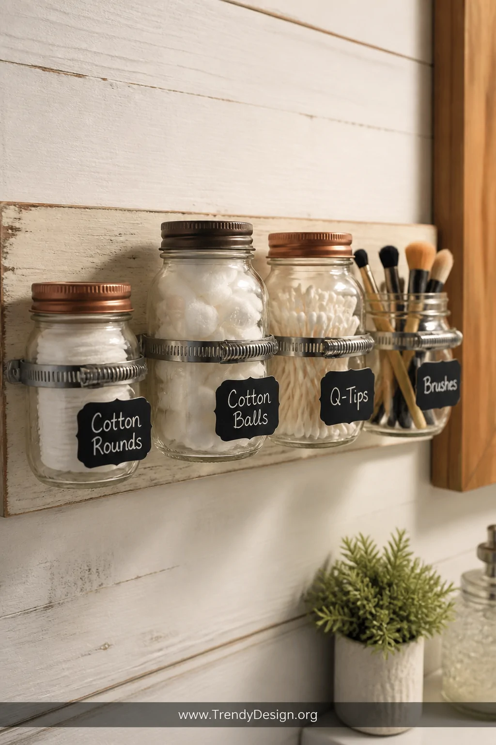 Close-up detail shot of a row of mason jars in mixed sizes mounted with hose clamps onto a painted wooden board hung on a whi