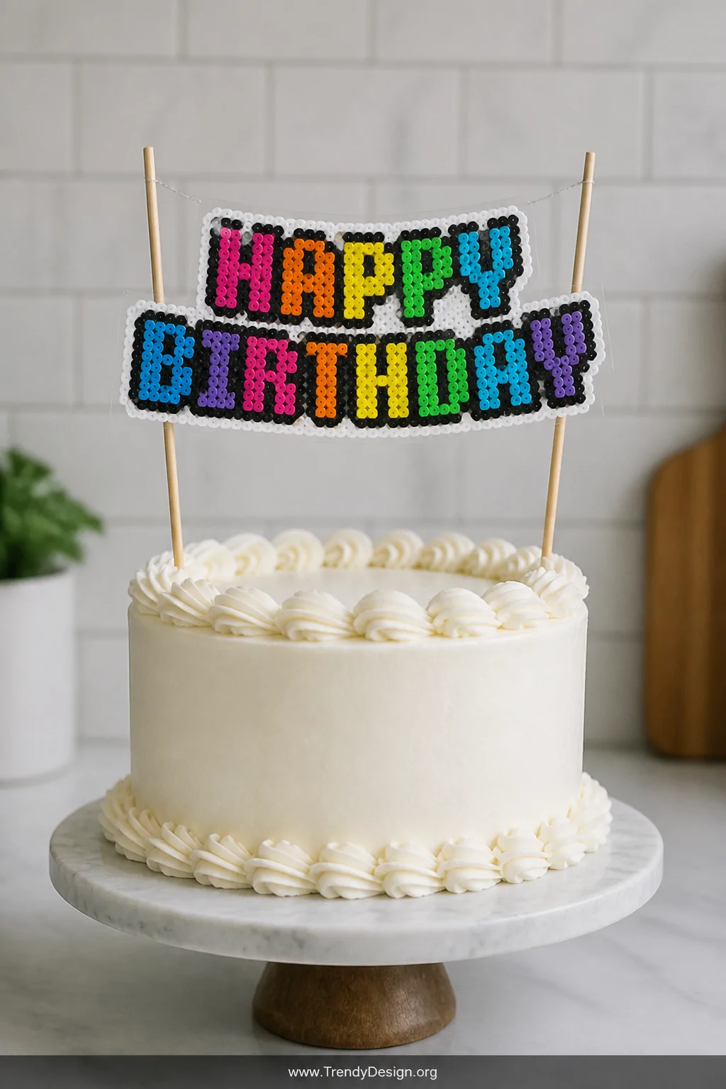 A medium closeup shot of a elegantly frosted white birthday cake on a marble cake stand, topped with a handmade Perler bead 