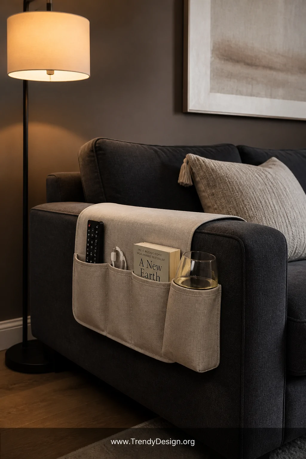 A medium shot of a relaxed living room sofa corner featuring a warm greige linen sofa armrest caddy draped neatly over the ar