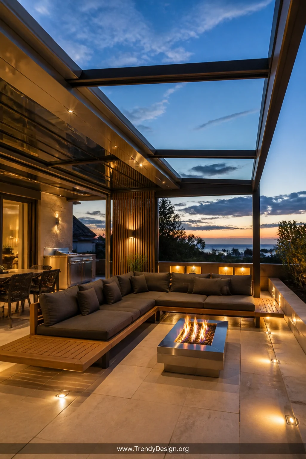 A wide shot of a high-end contemporary outdoor living space featuring a motorized track-mounted sliding glass panel retractab
