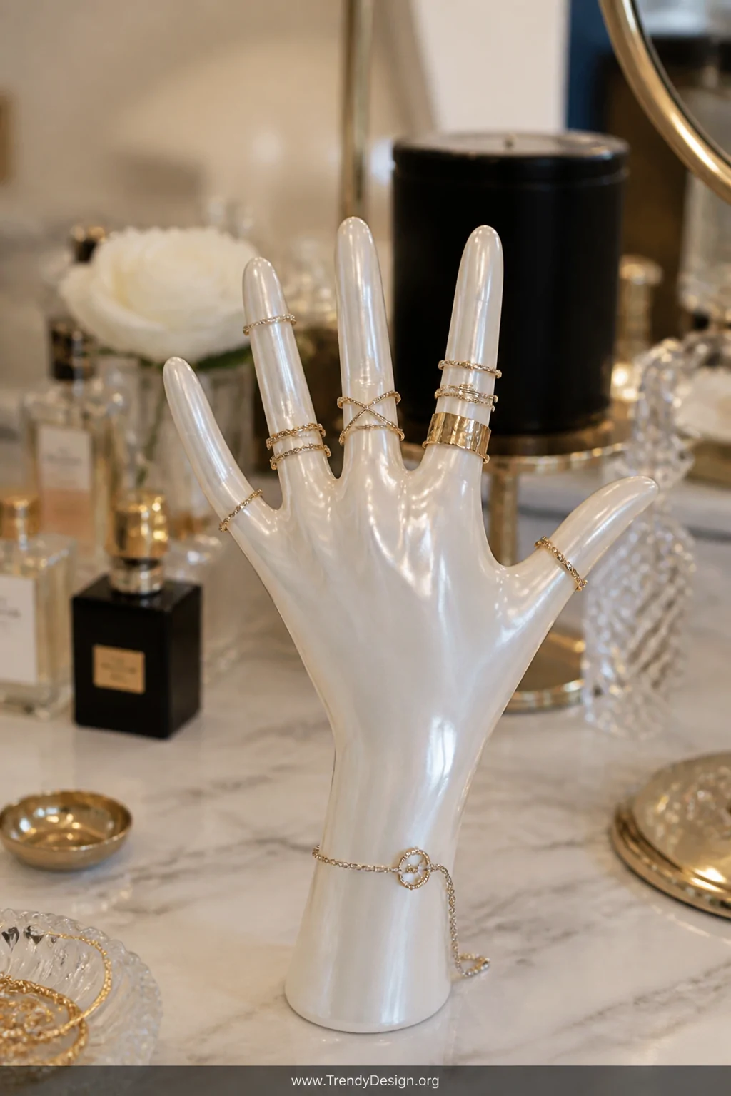 A medium closeup of a vanity tabletop displaying a pearlescent white wax hand with fingers spread wide, delicate gold and sil