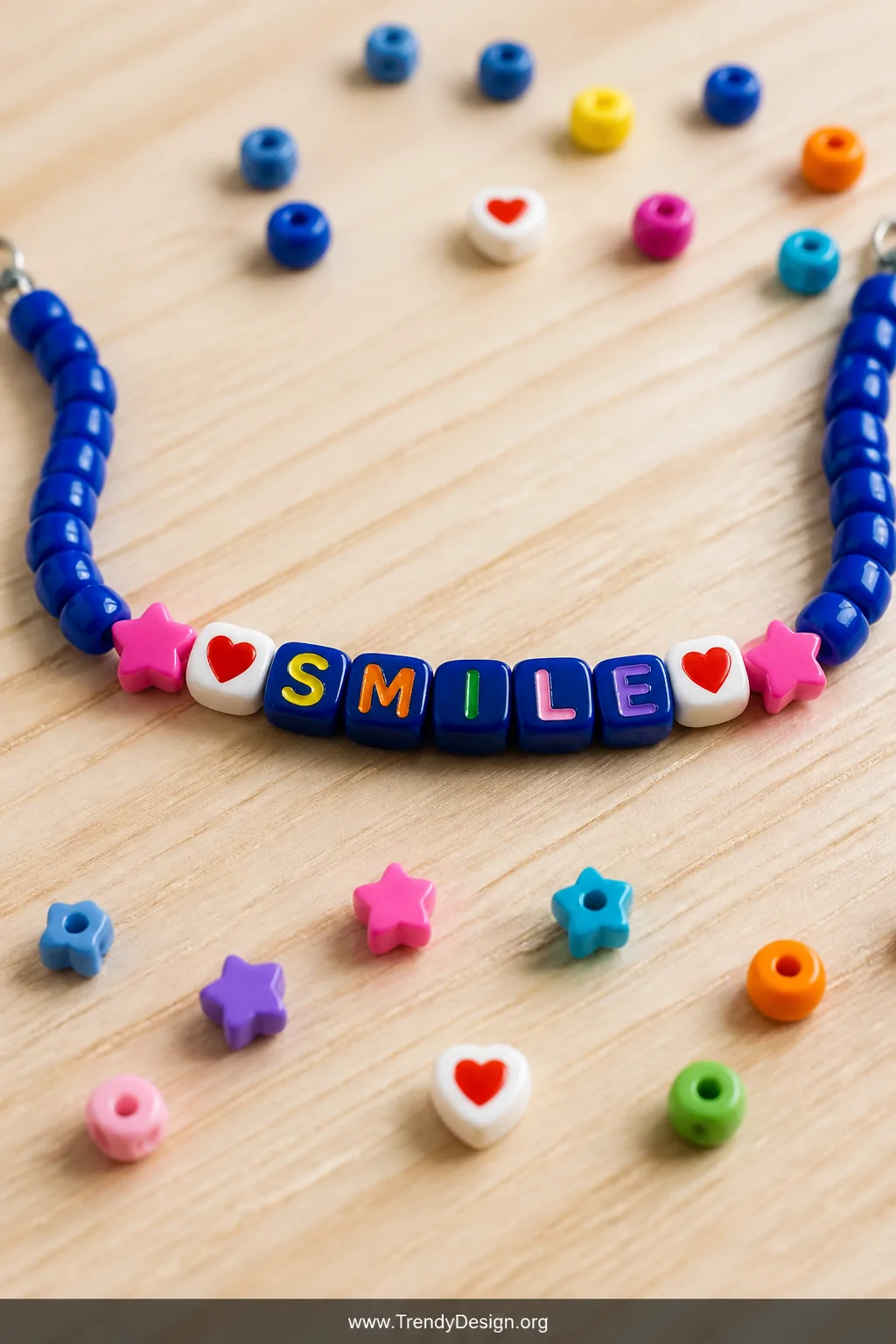 A medium close-up shot on a pale pine wood desk surface showing a colorful alphabet pony bead necklace spelling a short word 