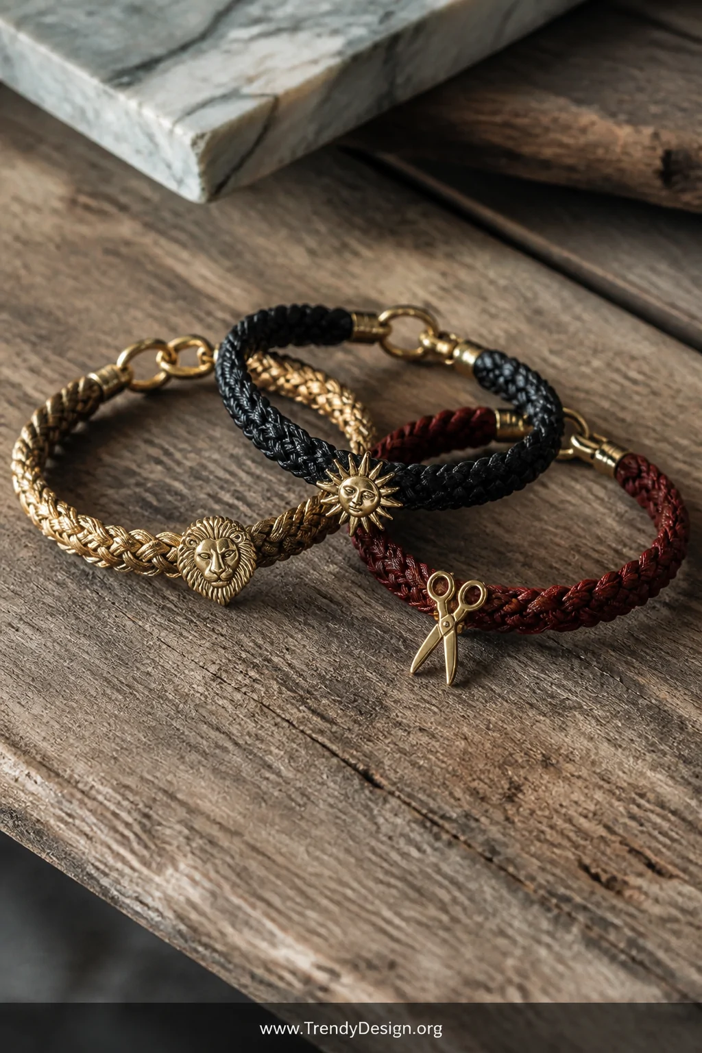 A closeup detail shot on a weathered wooden surface showing three braided bracelets made from leather cord in gold, black, an