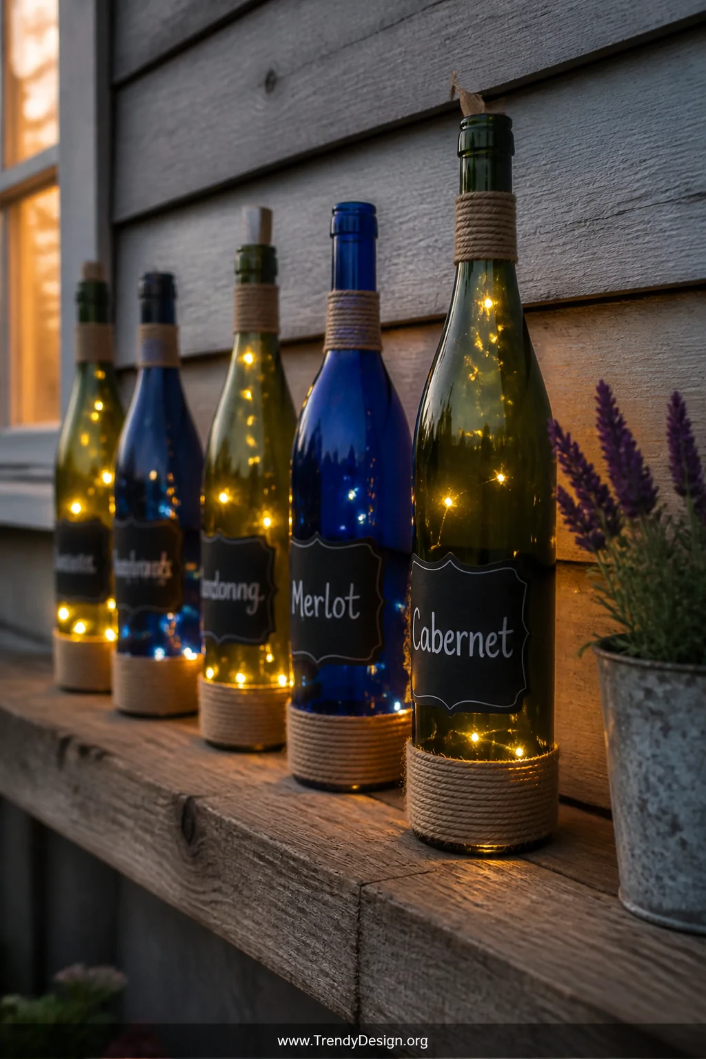 A medium shot of a row of deep green and cobalt blue wine bottles converted into lanterns, mini string lights glowing warmly 