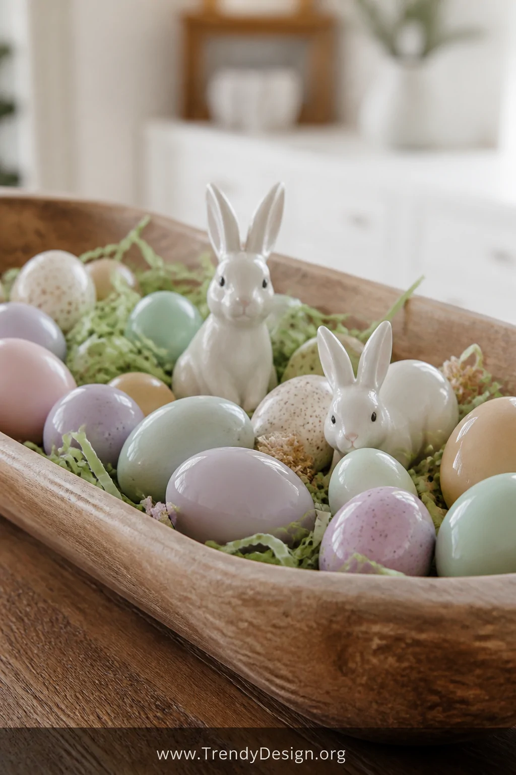 A close-up detail shot of a wooden dough bowl filled with a charming Easter vignette featuring pastel-painted eggs in soft la