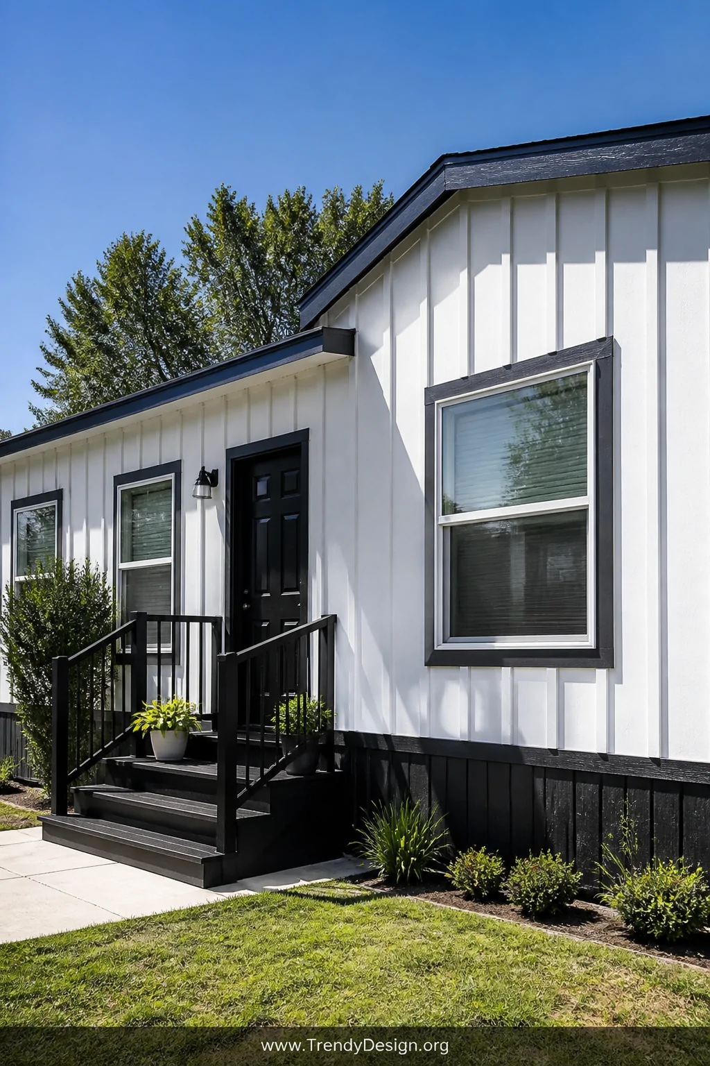 A wide exterior shot of a mobile home freshly resided in crisp white board and batten vertical siding with deep charcoal gray