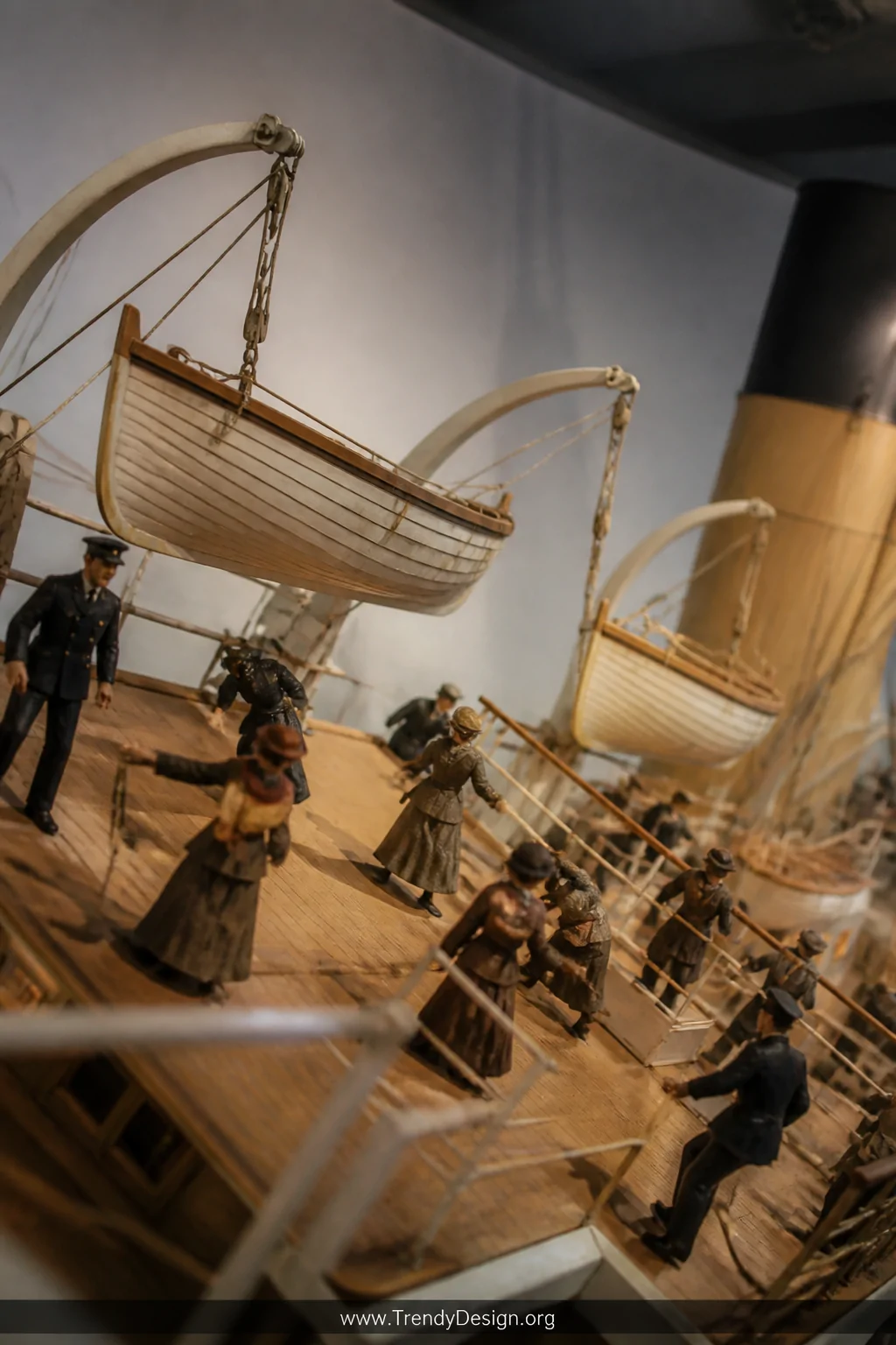 A medium shot of a Titanic lifeboat diorama scene showing tiny handmade wooden lifeboats suspended mid-air on fine craft wire