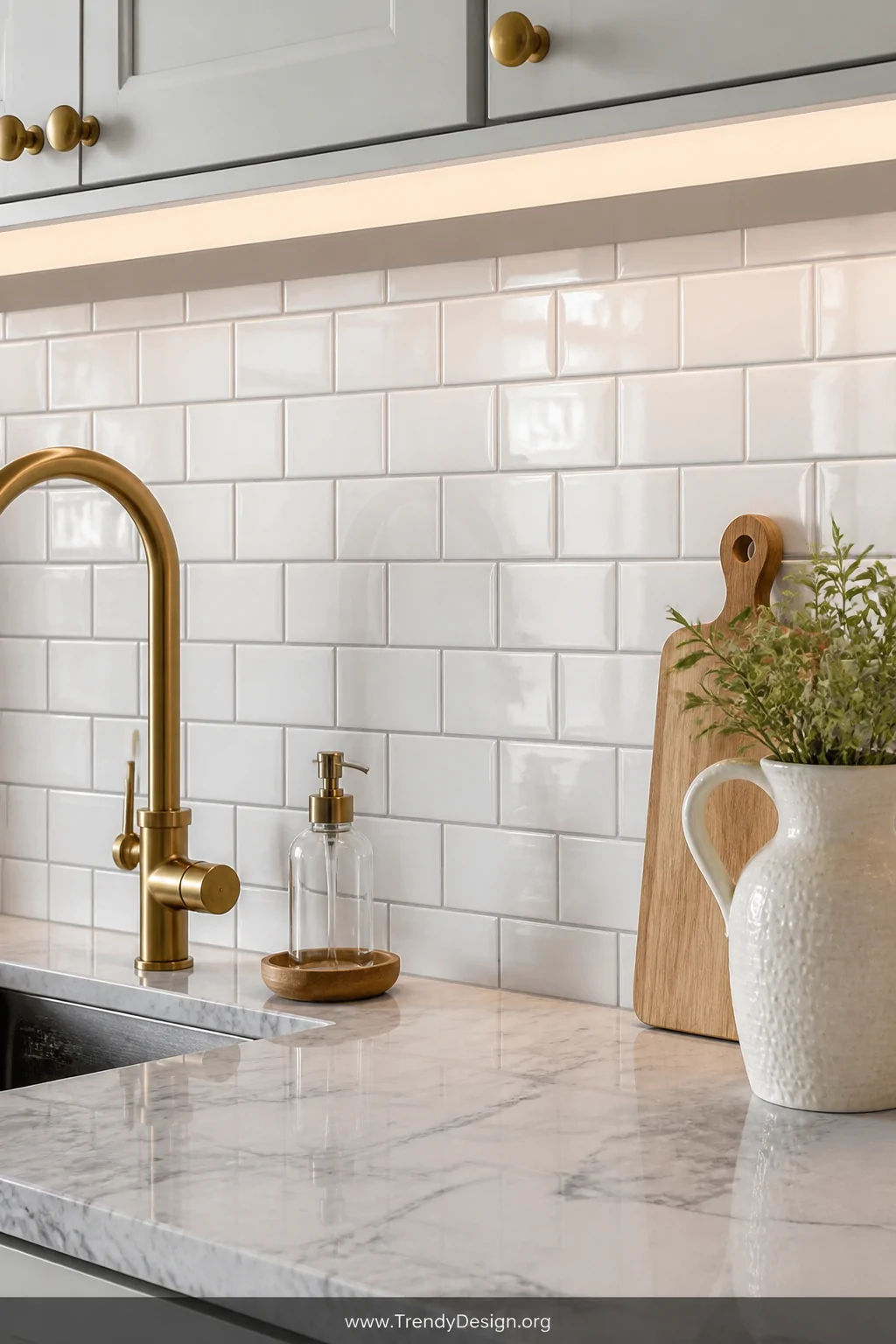 A bright kitchen backsplash area covered in glossy white subway tiles with clean grey grout lines, soft under-cabinet lightin