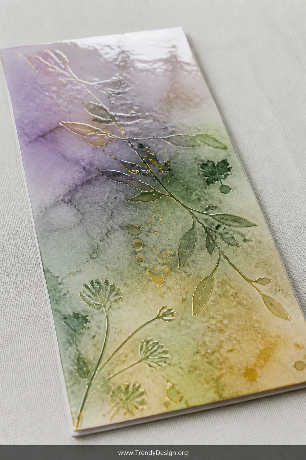 A close-up detail shot of a slimline card panel laid on a pale grey linen surface, displaying a loose organic watercolor wash