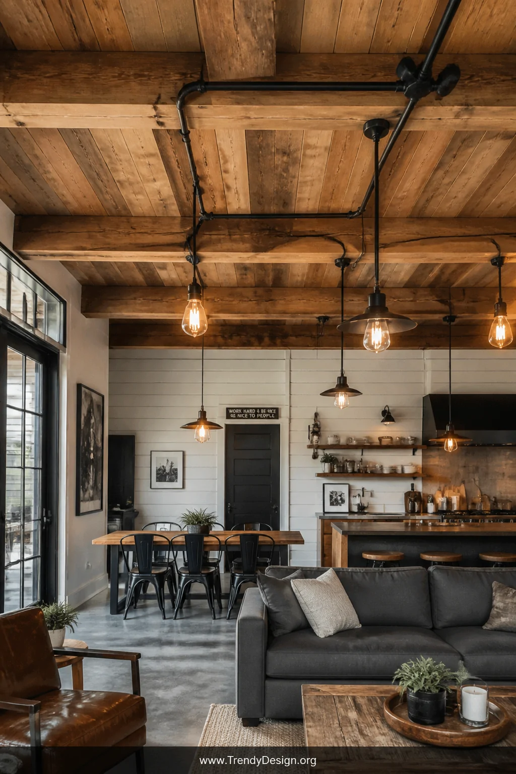 Wide shot of a rustic-industrial living space where matte black metal conduit is routed along a ceiling featuring reclaimed w