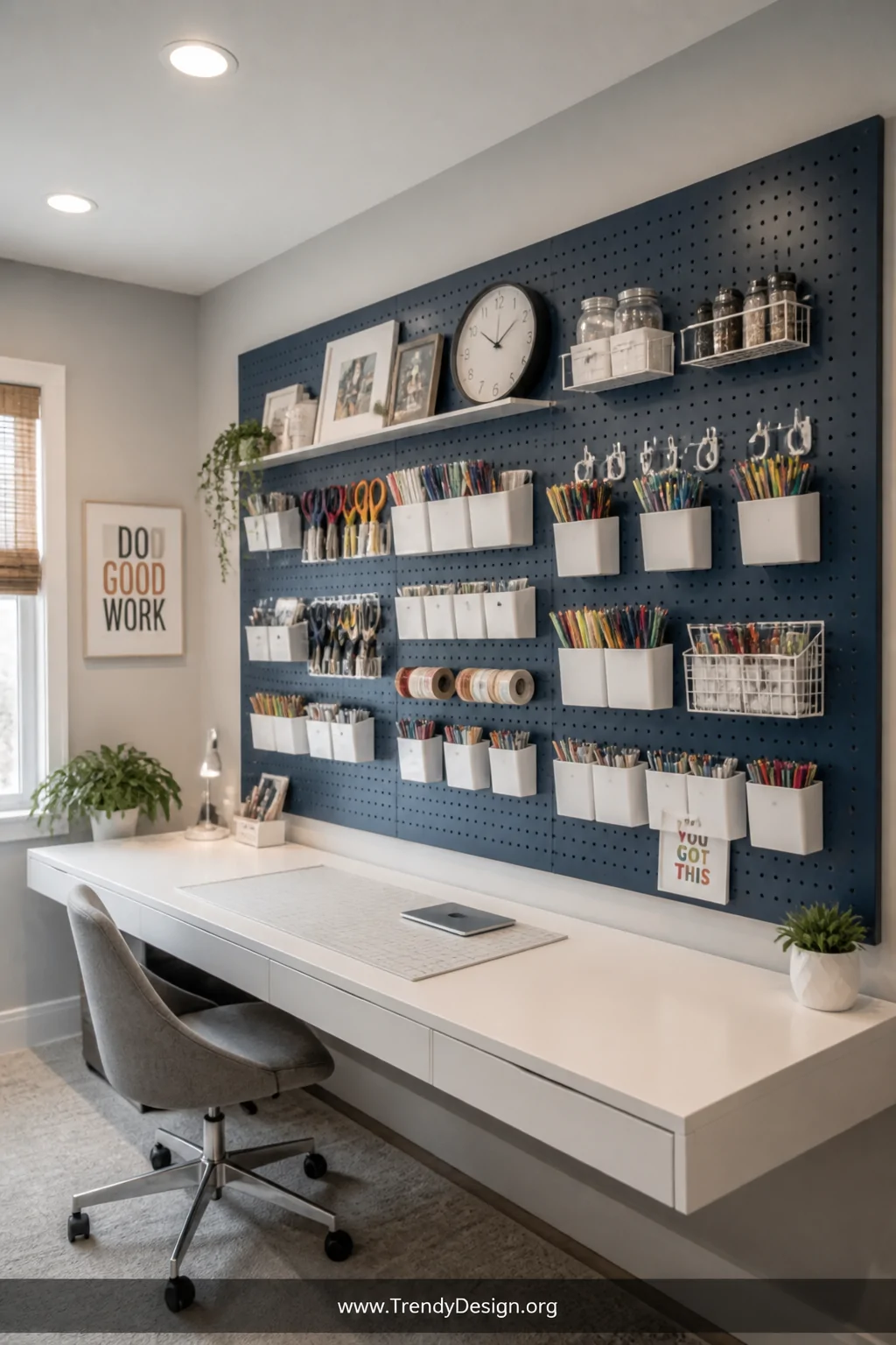 A wide shot of a well-lit home office or craft room featuring a large dusty navy blue painted pegboard covering most of one w