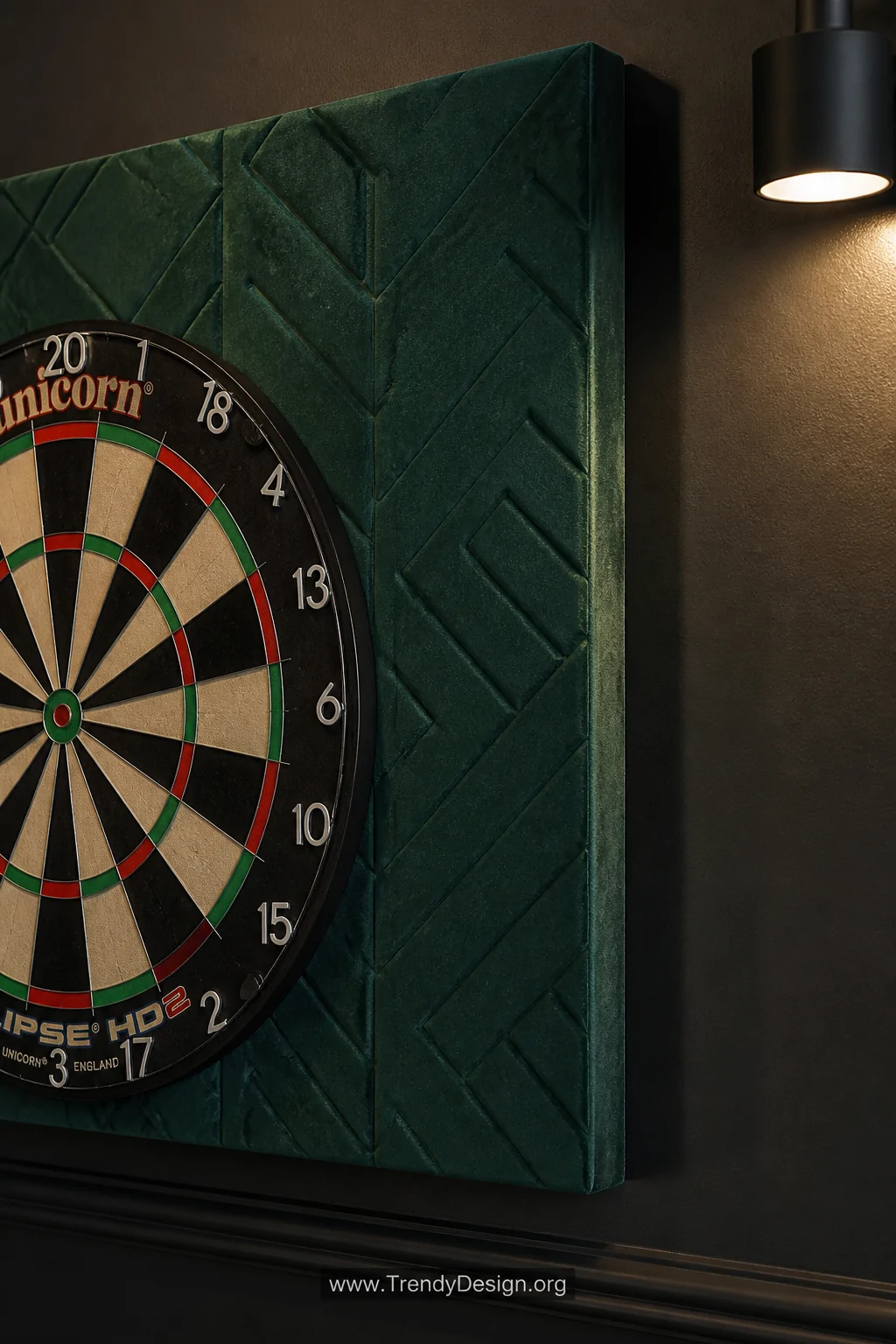 A detail closeup shot of a fabric-wrapped acoustic panel mounted behind a dartboard, the panel covered in deep emerald velvet