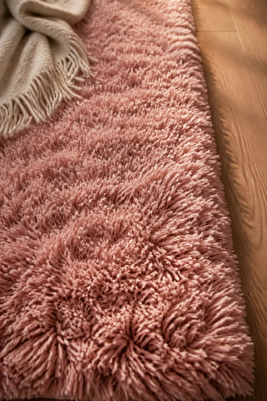 Close-up detail shot of a thick, high-pile blush pink shag rug with deep, sink-in texture, the individual soft fibers catchin